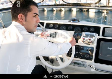Junger eleganter Mann bei der Yachtkontrolle Stockfoto