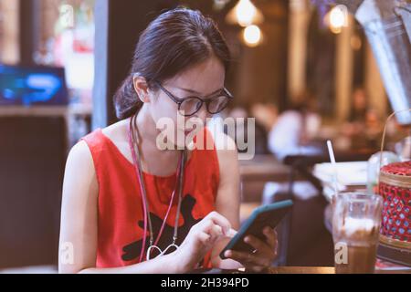 Frau, die eine Brille mit einem Smartphone trug, während sie im Café saß. Stockfoto