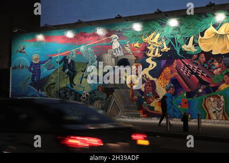 Nachtansicht von Rücklichtern, die an einem gemalten Wandgemälde von Künstlern aus dem Groundswell und Raul Ayala vorbeiragen, das berechtigt ist, ein Portal auf der Bowery Mural Wall zu öffnen Stockfoto