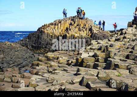 Besucher können sich am Giant’s Causeway in der Grafschaft Antrim an der Nordküste von Nordirland über die natürlichen vulkanischen Basaltsteinformationen hinwegschallen. Stockfoto