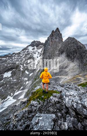 Wanderer, die Berge unter dramatischen Wolken betrachten, Blick vom Gipfel der westlichen Toerlspitze, hinten Partenkirchner Dreiterspitze Stockfoto