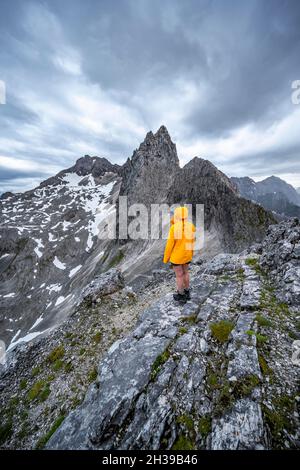 Wanderer, die Berge unter dramatischen Wolken betrachten, Blick vom Gipfel der westlichen Toerlspitze, hinten Partenkirchner Dreiterspitze Stockfoto