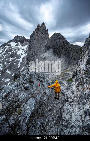 Wanderer, die Berge unter dramatischen Wolken betrachten, Blick vom Gipfel der westlichen Toerlspitze, hinten Partenkirchner Dreiterspitze Stockfoto