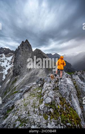 Wanderer, die Berge unter dramatischen Wolken betrachten, Blick vom Gipfel der westlichen Toerlspitze, hinten Partenkirchner Dreiterspitze Stockfoto