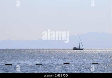 Blaue Meereswellen funkeln in der Sonne und eine Yacht. Sommerferien Konzept Stockfoto