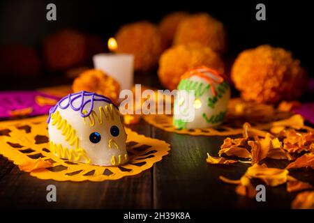 Zuckerschädel mit Kerze, Crepasuchil-Blüten oder Ringelblume und Papel Picado. Dekoration traditionell in Altären für die Feier des Tages verwendet Stockfoto