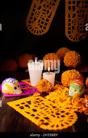 Zuckerschädel mit Kerzen, Cempasuchil-Blüten oder Ringelblume und Papel Picado. Dekoration traditionell in Altären für die Feier des Tages verwendet Stockfoto