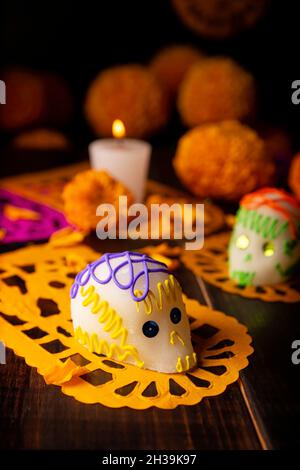 Zuckerschädel mit Kerze, Crepasuchil-Blüten oder Ringelblume und Papel Picado. Dekoration traditionell in Altären für die Feier des Tages verwendet Stockfoto