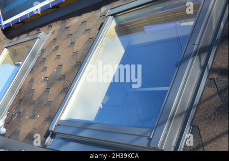 Dachfenster im Dachgeschoss auf dem Dach des Asphaltschindeln. Stockfoto
