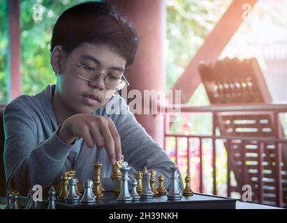 Konzentrierter ernster Junge, der Schachgambit entwickelt, Strategie, Brettspiel zum Sieger spielt. Lern-, Taktiken- und Analysekonzept. Stockfoto