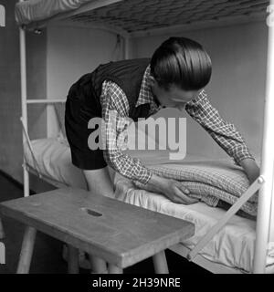 Junge in der Adolf-Hitler-Jugendherberge in Berchtesgaden beim Betten machen, Deutschland 1930er Jahre. Junge an den Adolf-Hitler-Jugendherberge Berchtesgaden Vorbereitung ihrer Betten, Deutschland 1930. Stockfoto