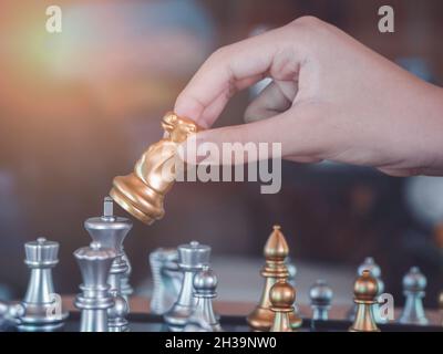 Hand Geschäftsmann bewegen den goldenen Ritter Schach kämpfen silbernen Ritter mit Feuer Funken Schach auf dem Schachbrett erfolgreich im Wettbewerb. Manag Stockfoto