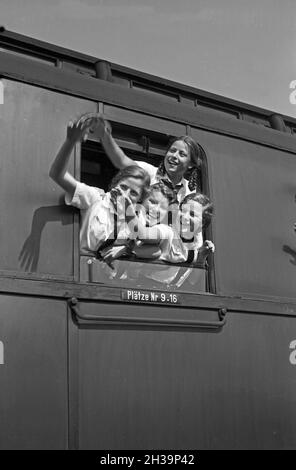 BDM Mädel winken aus ihrer Zugteilfenster bei der Fahrt in die Ferien, Deutschland 1930er Jahre. BDM-Mädchen jubeln aus dem Fenster ihres Zuges, der sie zu ihren Ferien bringt, Deutschland in den 1930er Jahren. Stockfoto