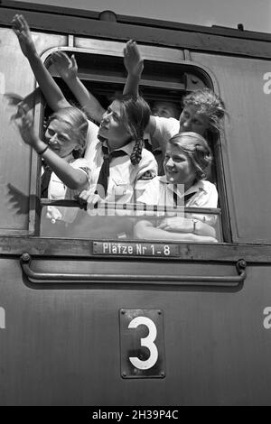 BDM Mädel winken aus ihrer Zugteilfenster bei der Fahrt in die Ferien, Deutschland 1930er Jahre. BDM-Mädchen jubeln aus dem Fenster ihres Zuges, der sie zu ihren Ferien bringt, Deutschland in den 1930er Jahren. Stockfoto