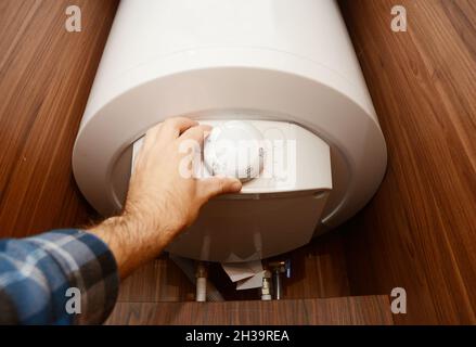 Man Hand regulieren die Wärme im Brennwertkessel, Combi Boiler für Haus Energieeinsparung. Konzept Für Gaskessel, Kesselversorgung. Stockfoto