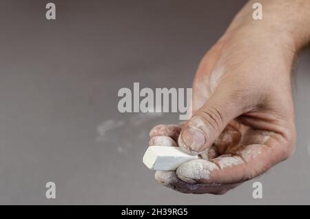 Die Hand eines erwachsenen Mannes hält ein Stück weiße Kreide. Selektiver Fokus. Stockfoto