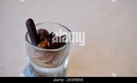 Schokolade- und Vanillepudding mit einer Schokoladenstäbchen-Wüste, serviert in einem Schnapsglas Stockfoto