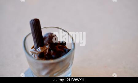 Schokolade- und Vanillepudding mit einer Schokoladenstäbchen-Wüste, serviert in einem Schnapsglas Stockfoto