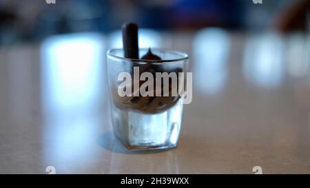 Schokolade- und Vanillepudding mit einer Schokoladenstäbchen-Wüste, serviert in einem Schnapsglas Stockfoto