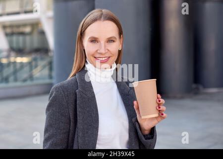 Frau mit Kaffee in der Hand auf der Straße. Geringe Schärfentiefe Stockfoto