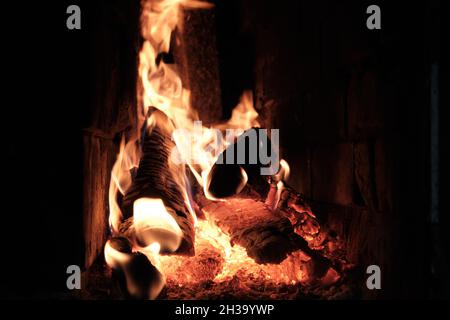 Ein Feuer brennt in Einem Ziegeldorf Ofen. Flammen, heiße Kohlen und Protokolle. Stockfoto