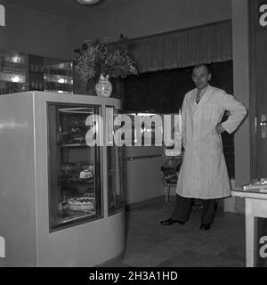 Ein junger Mann an der Theke seiner Konditorei, Deutschland 1950er Jahre. Ein junger Mann an der Theke seines Cafés, Deutschland der 1950er Jahre. Stockfoto