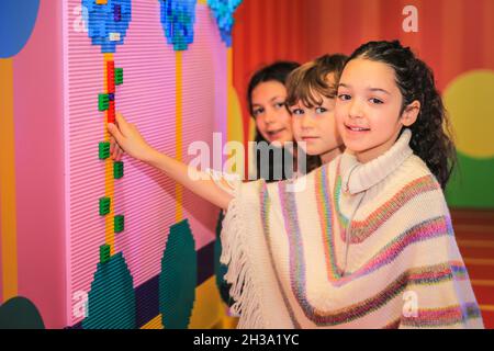 Shoreditch, London, Großbritannien. Oktober 2021. Poppy (r) und ihre Freunde spielen in der Installation. Die preisgekrönte Künstlerin und Designerin Yinka Ilori hat sich mit der LEGO Group zusammengetan, um die ‘Waschsalon der Träume' zu schaffen, eine kostenlose, interaktive Kunstinstallation in London, die vom kreativen Optimismus und der Widerstandsfähigkeit von Kindern inspiriert ist und wie sie die Welt um sie herum aufbauen. (Kinder zum Fotografieren freigestellt). Die Installation wird am 28. Oktober in London eröffnet und stellt sich einen Waschsalon der lokalen Gemeinschaft als ein spielerisches, interaktives und lebendiges Spiel vor. Quelle: Imageplotter/Alamy Live News Stockfoto