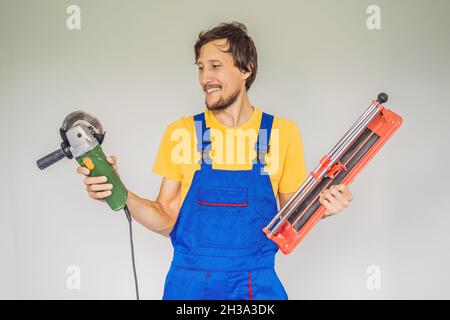 Ein Fliesenleger, ein Fliesenspezialist, hält einen Fliesenschneider in den Händen Stockfoto