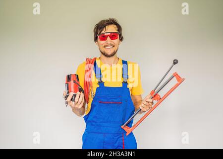 Ein Fliesenleger, ein Fliesenspezialist, hält einen Fliesenschneider in den Händen Stockfoto