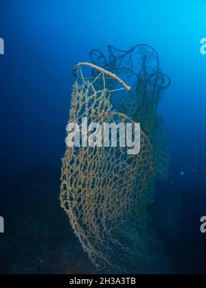 Ein altes, verlassene Fischernetz liegt auf dem Meeresboden in dunklen, trüben Gewässern Stockfoto