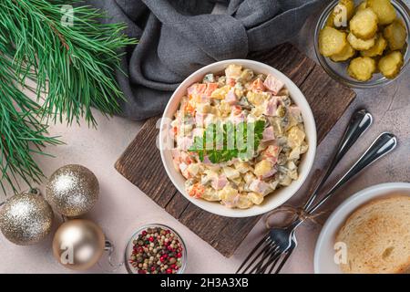 Traditioneller russischer Salat olivier auf dem Hintergrund von Tannenzweigen und Weihnachtsbaumspielzeug. Stockfoto