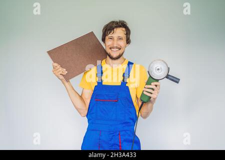 Ein Fliesenleger, ein Fliesenspezialist, hält einen Fliesenschneider in den Händen Stockfoto