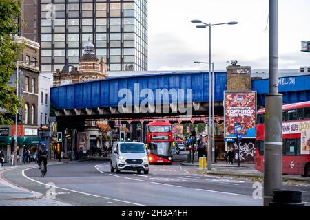 Blue Painted Railway Bridge Überqueren Sie Eine geschäftige London Street in Waterloo Central London mit Verkehrs- und öffentlichen Verkehrsmitteln sowie Einem einzigen Radfahrfahrer Stockfoto