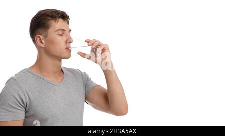 Schöner ruhiger muskulöser junger Kaukasier, der Wasser aus Glas trinkt, isoliert auf weißem Hintergrund Stockfoto