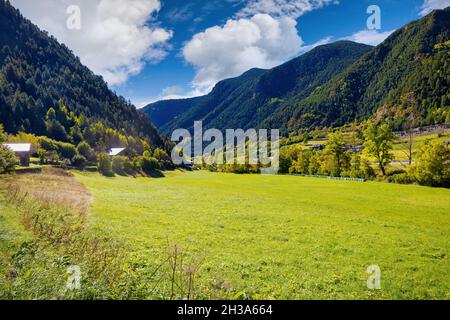 Blick auf eine von Wald und hohen Bergen umgebene Wiese im Herbst in Ordino, Andorra Stockfoto