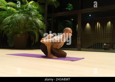 Omar Mura Mann mittleren Alters kaukasischen führt eine Yoga-Position in Innenräumen. Stockfoto