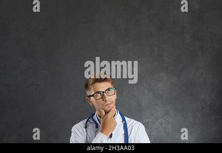 Verwirrt männlichen Arzt denken, zweifeln, reiben Kinn, unsicher, welche Wahl zu treffen Stockfoto