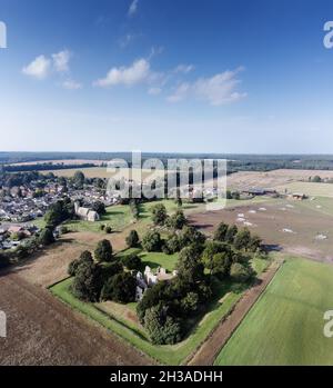 Luftbild über dem Dorf Weeting, Brandon in England mit der Kirche und den Ruinen von Weeting Castle im Vordergrund Stockfoto