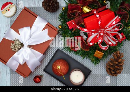 Weihnachtliche Tischdekoration mit einer Tasse Kaffee, zuckerbeschichteten Keksen, Duftkerze und roten Geschenkschachteln. Stockfoto
