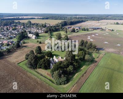 Luftbild über dem Dorf Weeting, Brandon in England mit der Kirche und den Ruinen von Weeting Castle im Vordergrund Stockfoto