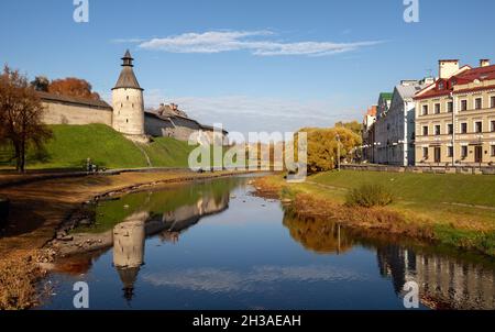 Pskov Herbst Stadtlandschaft. Blick auf die Mauern und Türme des Kremls mit Spiegelung in der Pskova und dem Goldenen Ufer Stockfoto