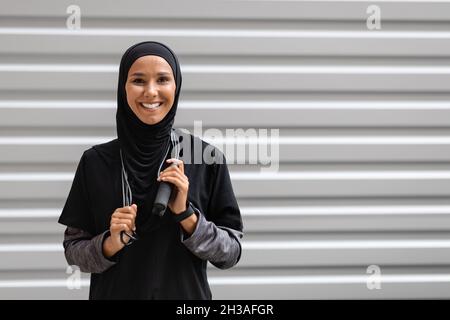 Outdoor-Sport. Happy Muslim Lady Trägt Bescheidene Sportswear Posiert Mit Springseil Stockfoto