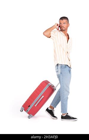 Isolierter Mann mit Reisekoffer, der am Handy herumläuft und spricht Stockfoto