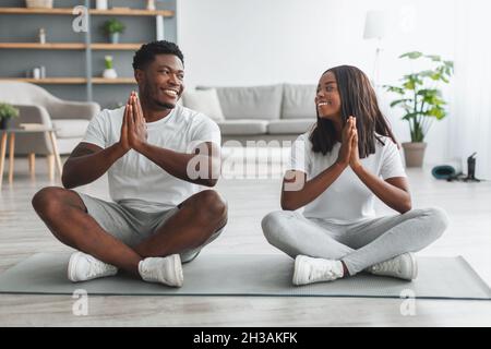 Schwarzes Paar meditiert und hält die Hände in Gebetshaltung zusammen Stockfoto