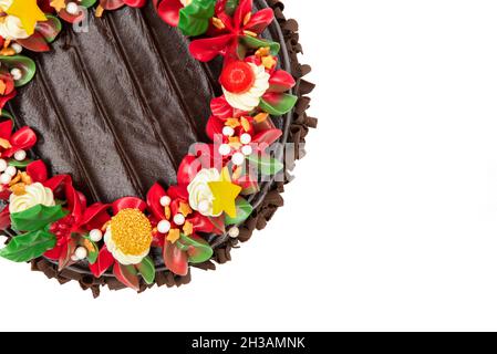 Draufsicht auf einen Schokoladenkuchen mit roten, weißen und grünen Blumen und Blättern. Stockfoto