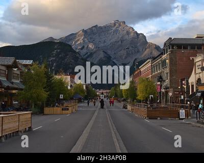 Stadtbild der Innenstadt von Banff in den kanadischen Rocky Mountains mit Geschäften und Touristen auf der Straße und dem majestätischen Cascade Mountain im Hintergrund. Stockfoto