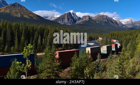 Atemberaubende Landschaft in den kanadischen Rocky Mountains von der berühmten Morant's Curve aus gesehen, mit einem Zug, der an einem sonnigen Tag im Herbst vorbeifährt. Stockfoto