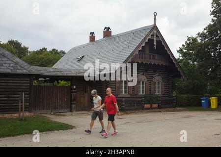 Die Besucher kommen an einem der traditionellen russischen Holzhäuser in der Russischen Kolonie Alexandrowka in Potsdam vorbei. Stockfoto