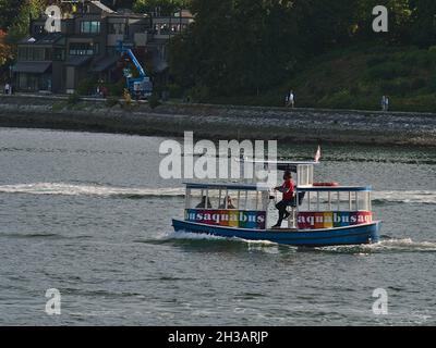 Blick auf das farbenfrohe Little Aquabus-Boot, das Fährverbindungen in False Creek Bay, Vancouver Downtown bietet, mit Menschen, die an einem sonnigen Tag im Herbst vorbeifahren. Stockfoto