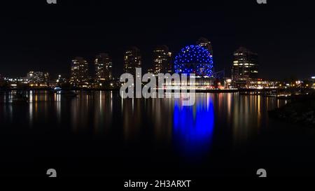 Atemberaubender Blick auf die Bucht von False Creek, Vancouver mit blau glänzender Science World und beleuchteten Gebäuden, die sich nachts im glatten Wasser spiegeln. Stockfoto